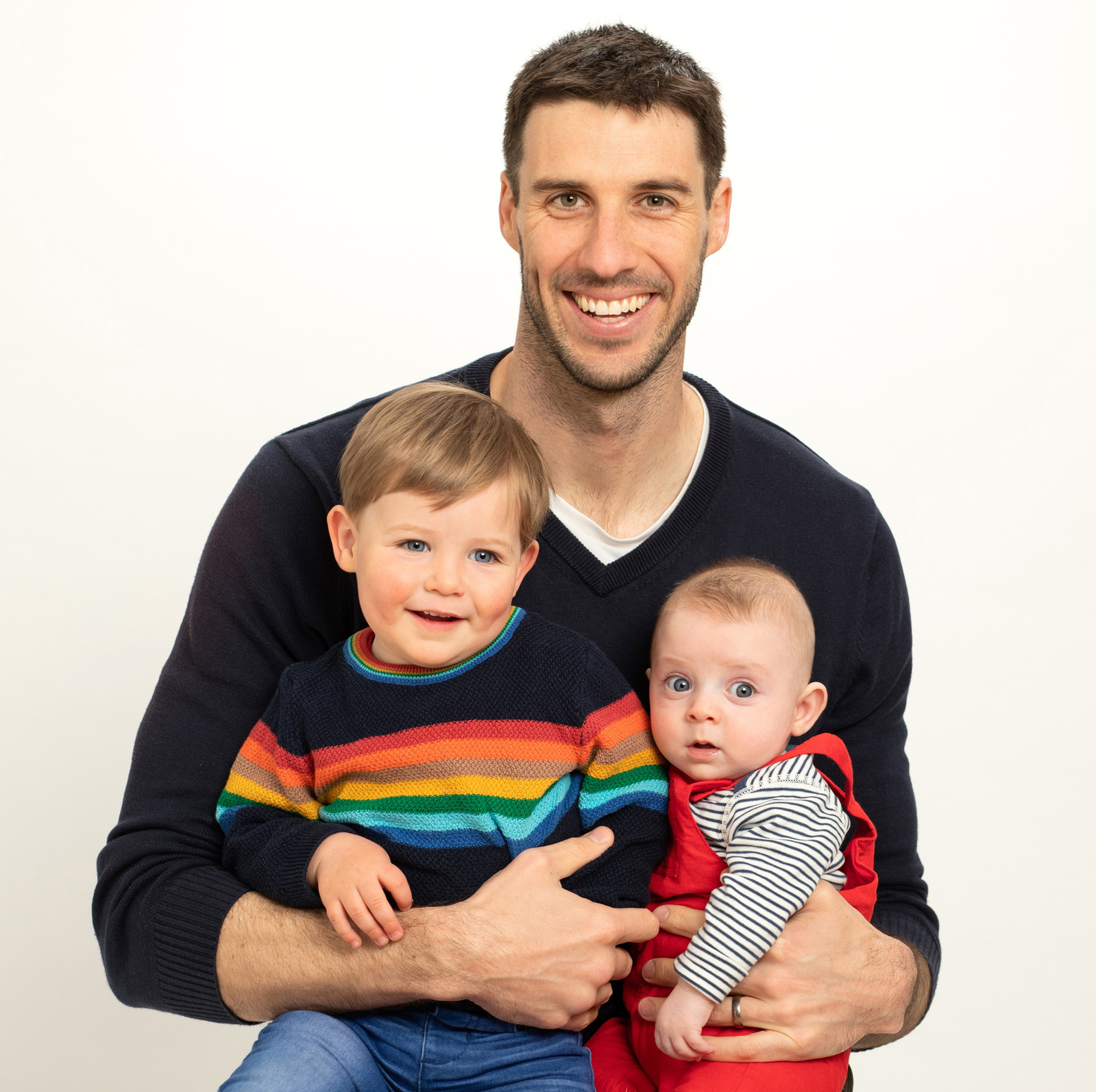 Classic portrait of a young Dad and his two small children photographed in a professional family photography studio in Dublin white background