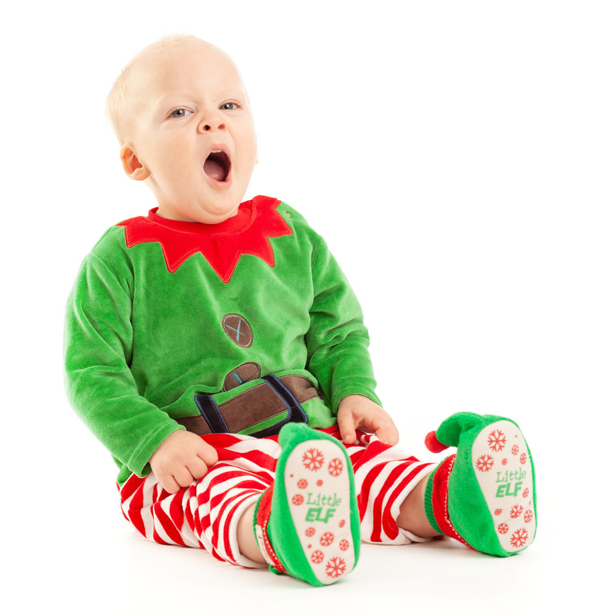 Christmas portrait of a little boy in elf costume yawning in a professional family portrait photography studio with white background 