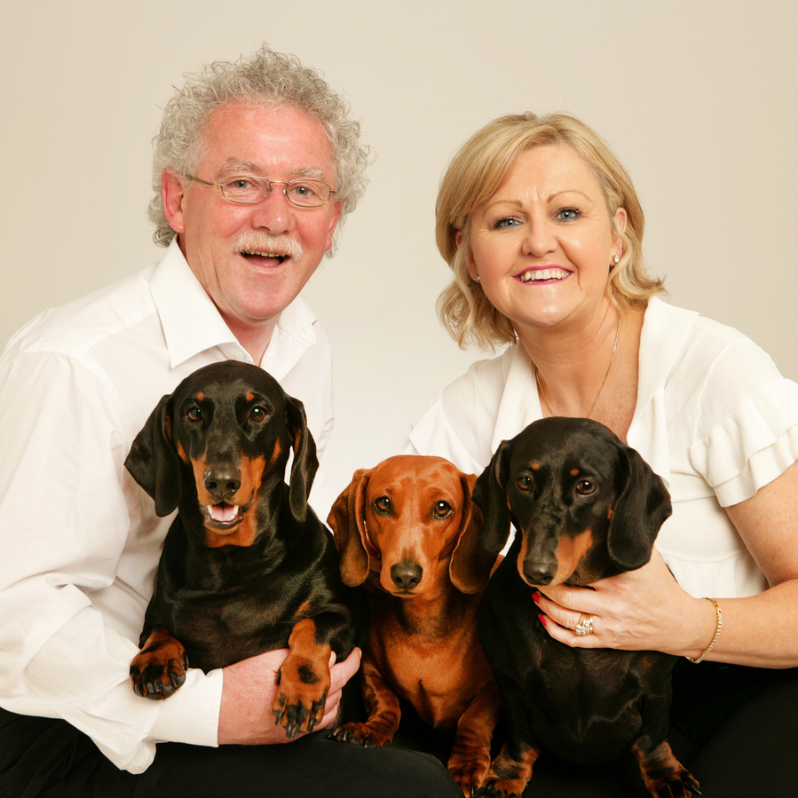Classic pet owner portrait photography a couple with their three family dogs in professional pet photo studio in Dublin