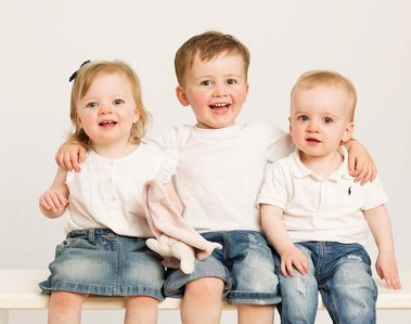 Professional portrait of two Young Brothers and sister laughing wearing white t shirts & blue denim, studio family portrait photography