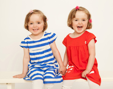 Twin sisters sitting on a bench in professional family photography studio Dublin www.1portrait.ie