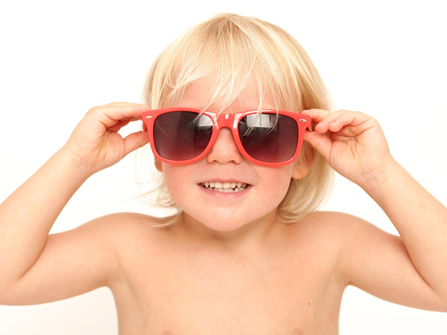 Young blonde boy wearing oversized red sunglasses. Portrait taken in professional family portrait studio with white background www.1portrait.ie