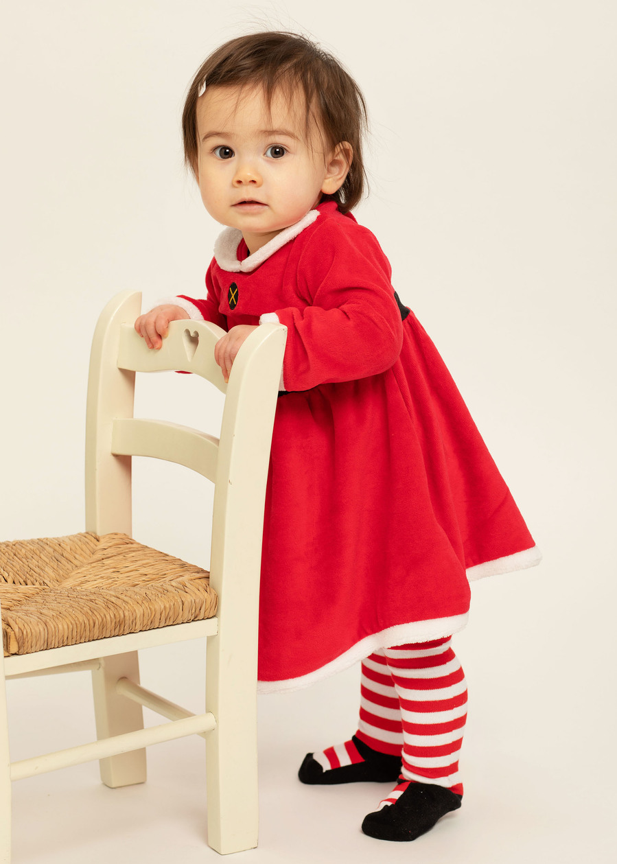 Christmas portrait of a little girl wearing a red Christmas Santa dress  in a professional family portrait photography studio with white background 