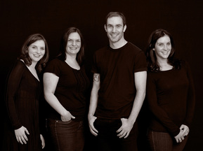 Professional family portrait of four grown up siblings in photography studio with black background