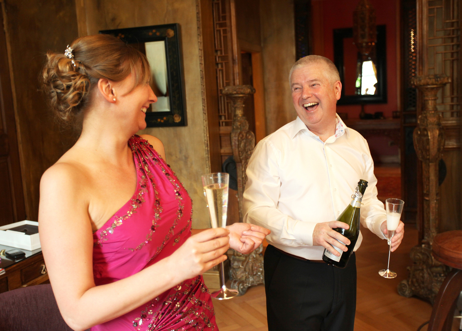 Lively fun portrait of bride and groom drinking champagne and laughing reportage style photography