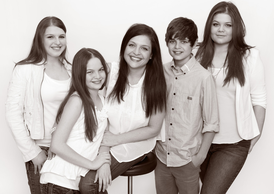 Professional family portrait photo of four children, brothers, and sisters and their mother wearing white shirts smiling and laughing in a photography studio Dublin
