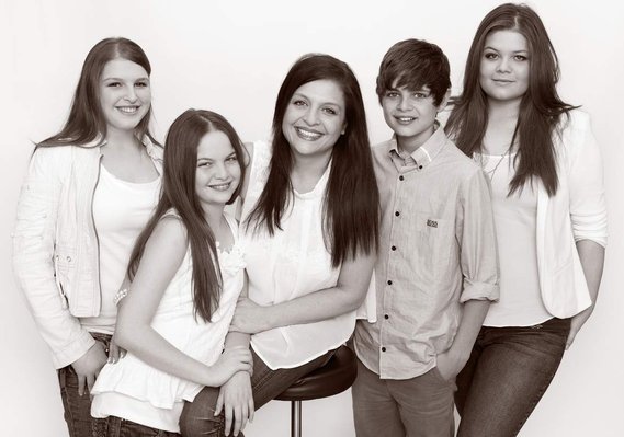 Professional family portrait photo of four children, brothers, and sisters and their mother wearing white shirts smiling and laughing in a photography studio Dublin 