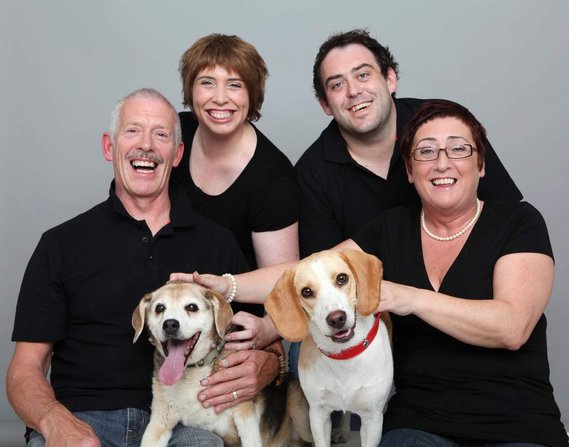Family portrait of parents and grown up children with two dogs in professional photo studio grey background