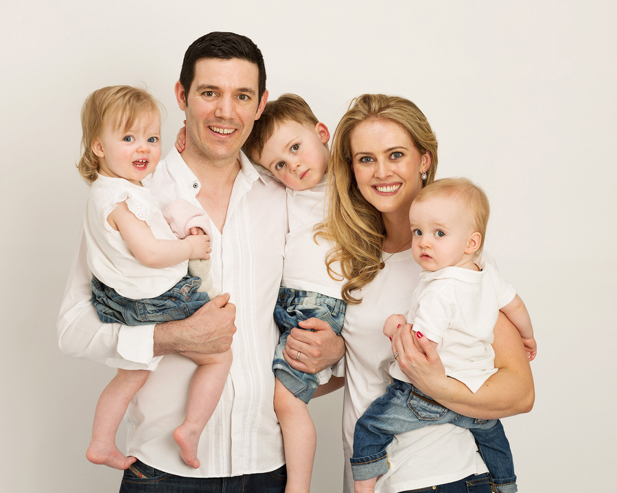 Family portrait of Mother, father and three young children in a professional photography studio in Dublin white background