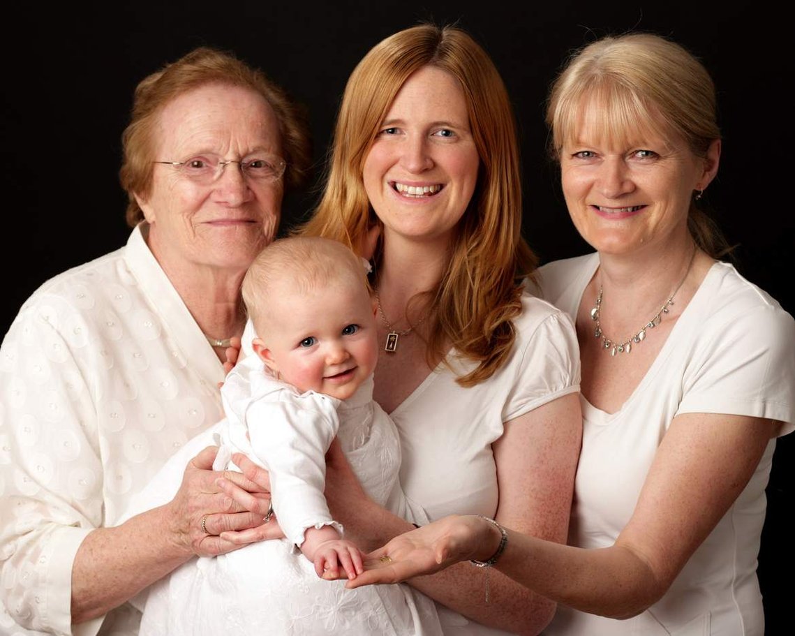 Four Generations studio portrait of Great Grandmother, Grandmother, Mother and Baby Daughter professional photography studio black background 