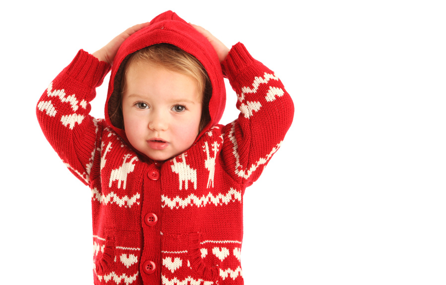 Christmas portrait of a little girl wearing a red Christmas jumper with hood in a professional family portrait photography studio with white background 