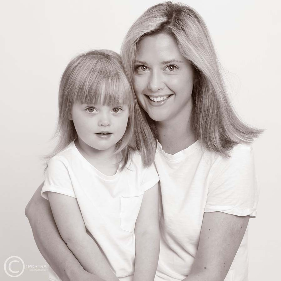 Classic black and white portrait of a mother and her young daughter wearing white taken in a professional family photography studio in Dublin white background