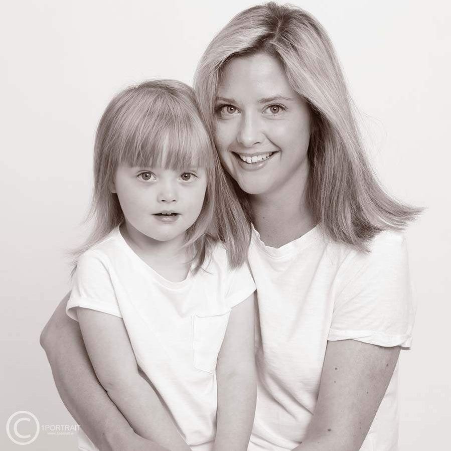 Professional photographer studio portrait of mother and daughter wearing white
