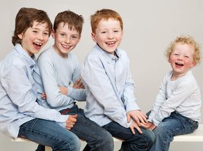 Children's family portrait of four brothers in blue shirts laughing professional portrait photography studio Dublin