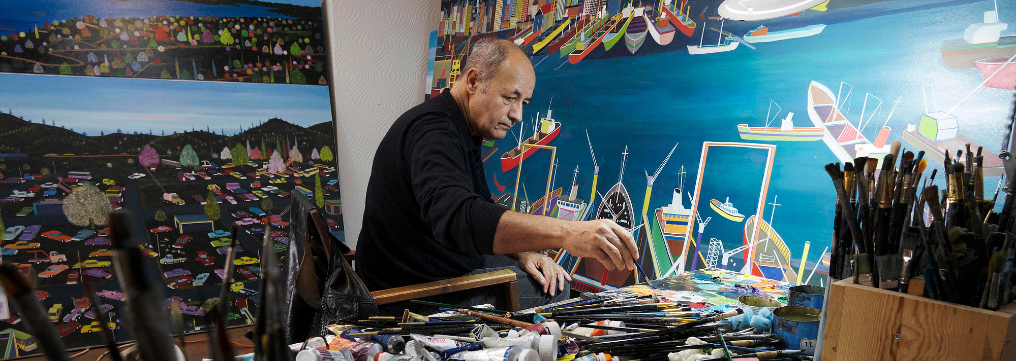 The naive painter Bayram Gümüş is painting in his  workshop.