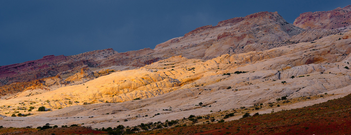 San Rafael Swell in southern Utah with storms moving in and a shaft of light hitting the red rock cliffs 