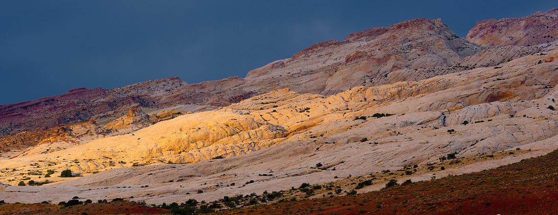 San Rafael Swell in southern Utah with storms moving in and a shaft of light hitting the red rock cliffs 