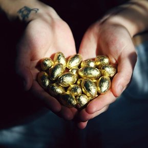 Purple Raindrop consultant with their hands in a heart shape holding a handful of golden eggs to show value