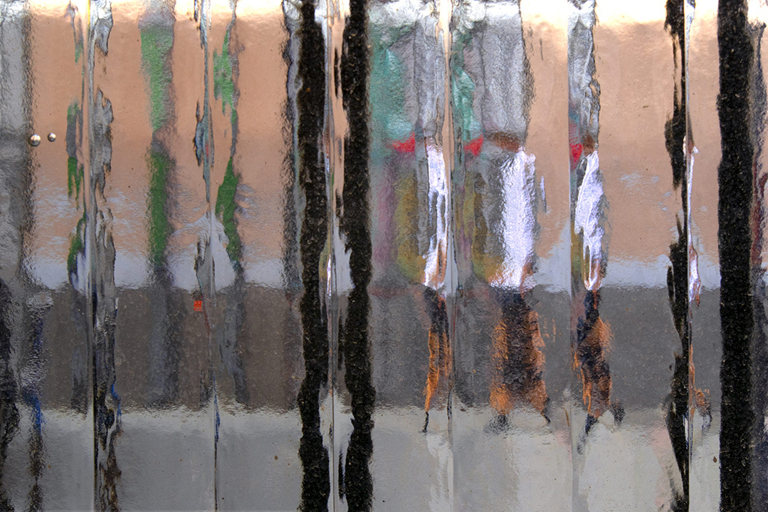 Street level photograph of a pedestrian on a Madrid street through a distorting window