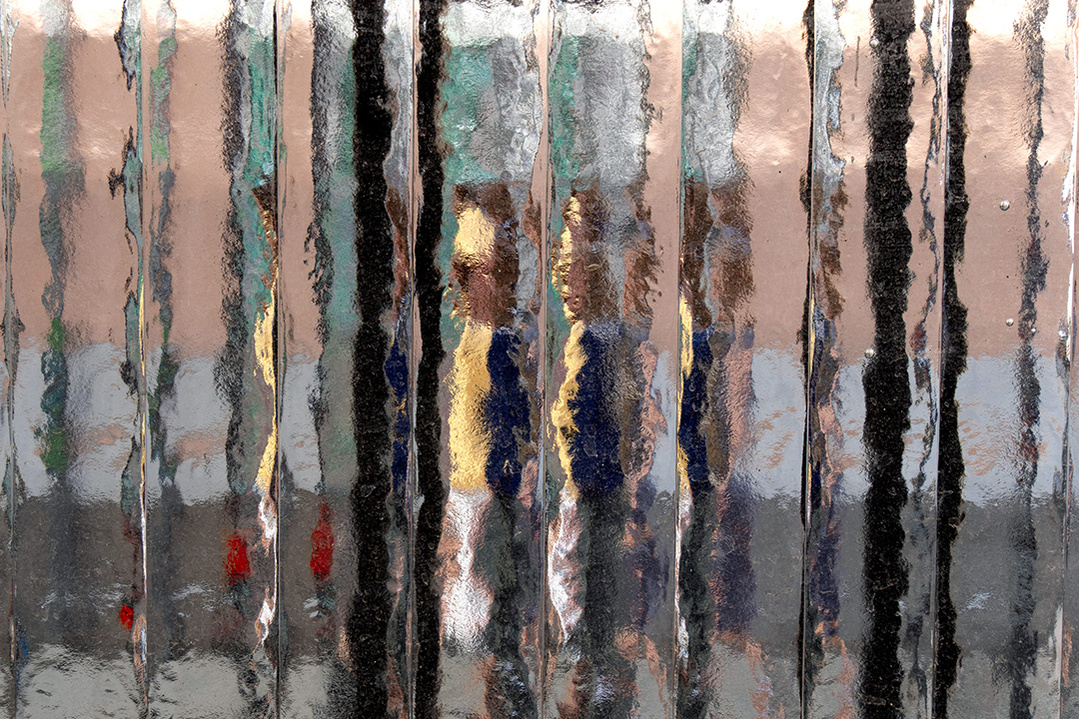 Street level photograph of a pedestrian on a Madrid street through a distorting window