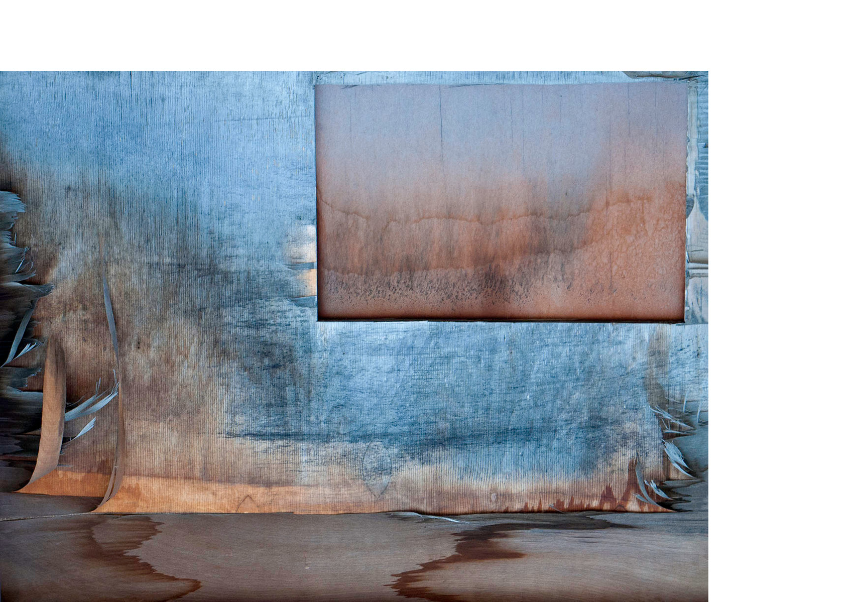 Water marks on a board covering a basement window that resemble a landscape