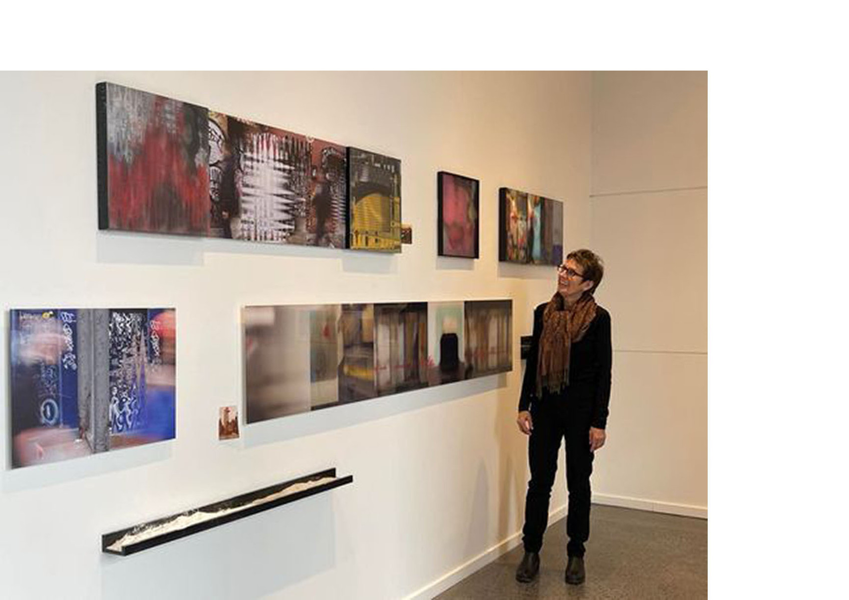 Woman standing in front of art work handing on a wall as an gallery exhibition
