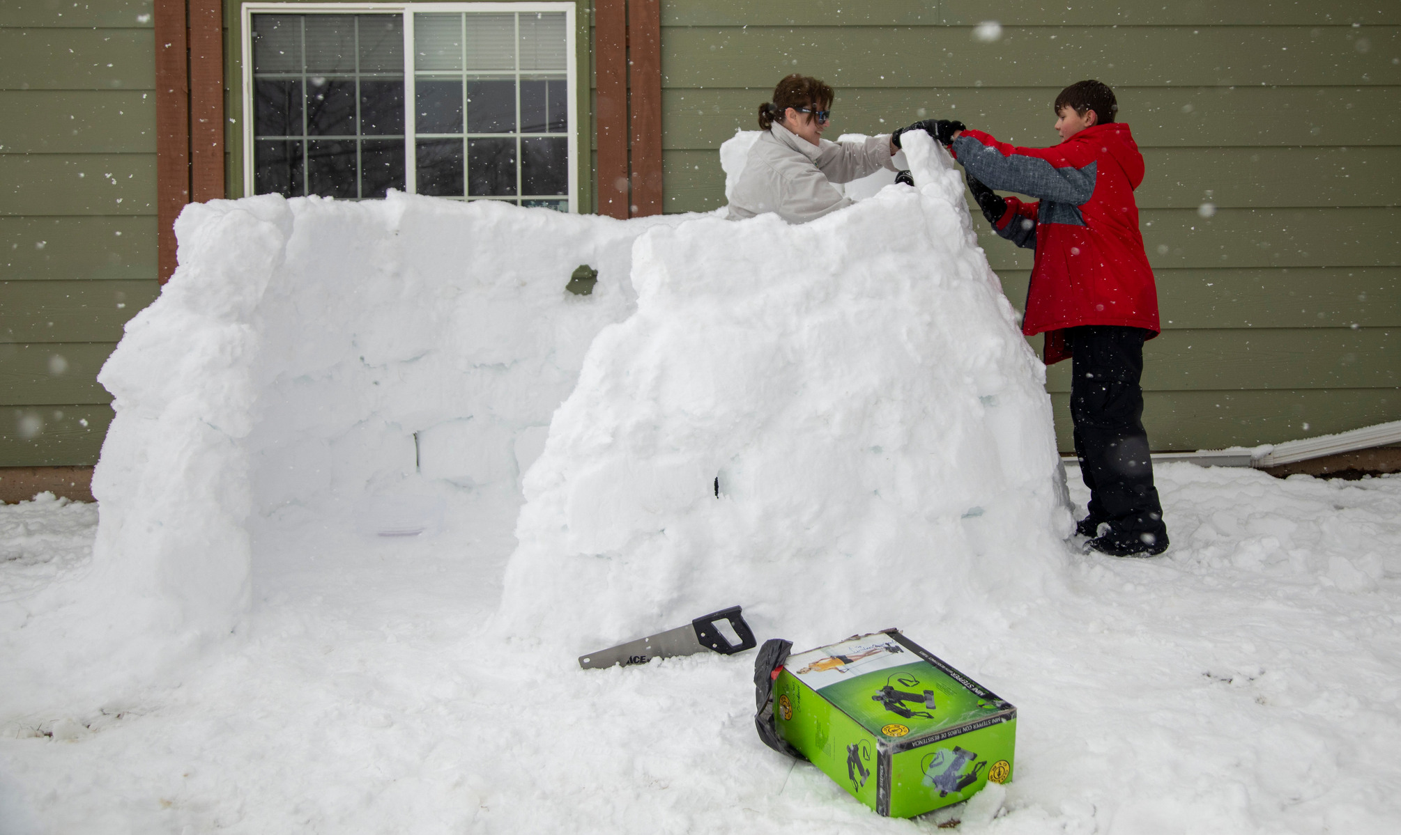 Diane McDonald (left) builds an igloo out of snow in her yard with neighbor Jayden Eiesland, 11, on Monday, March 15, 2021, in Rapid City, S.D. McDonald said she usually builds snow structures with her grandchildren, but since her grandchildren were not a