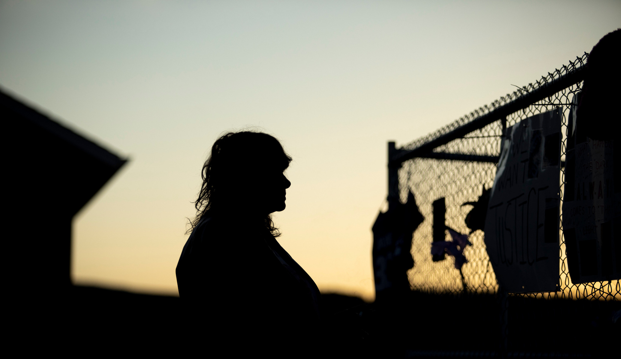 Hideaway Hills resident Sheri Stacy looks at signs posted on a fence surrounding evacuated homes near a collapsed gypsum mine during a vigil on Tuesday in Blackhawk. Stacy said she wanted to sell her house before the mine collapsed and cannot get a realto