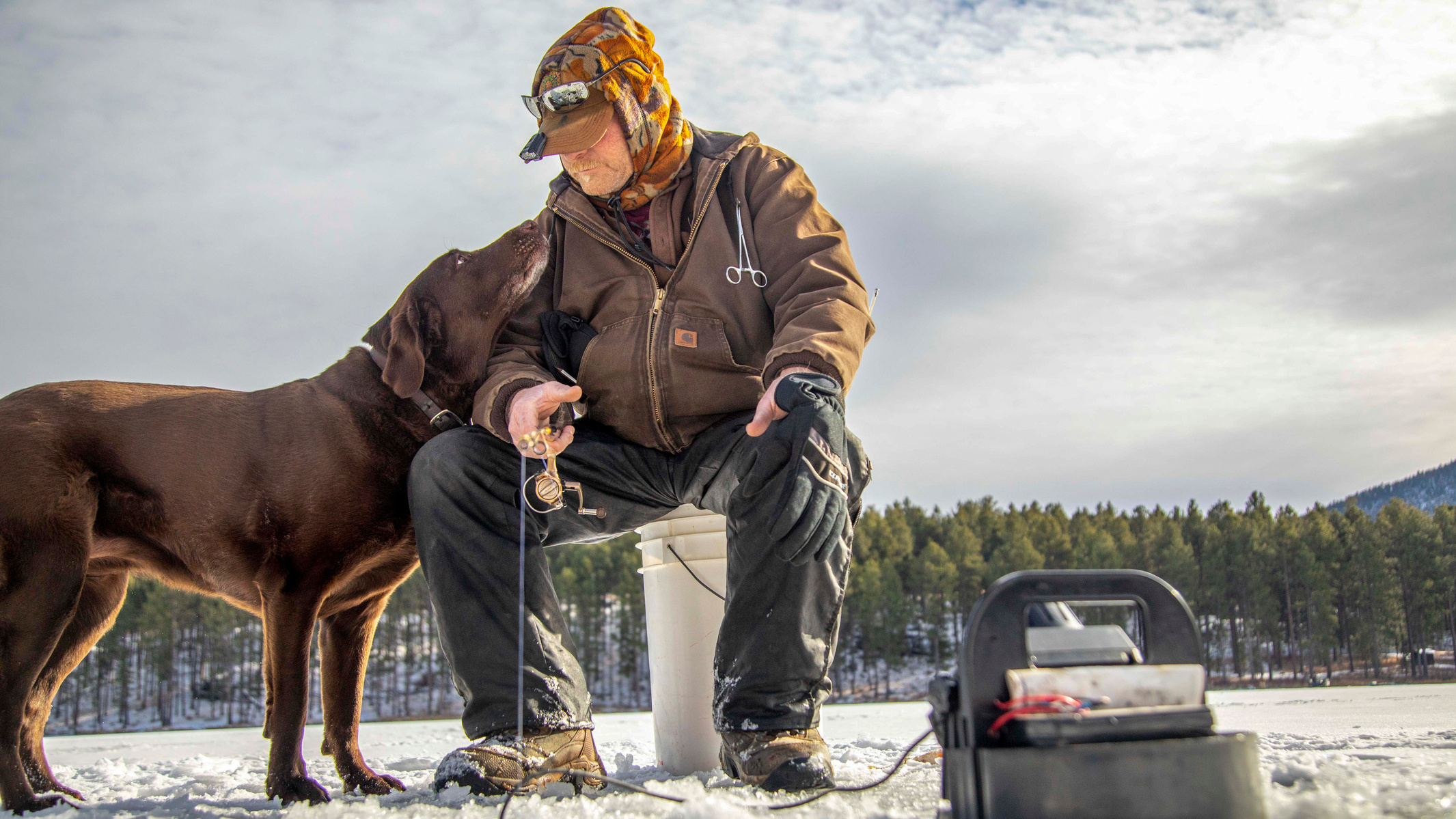 Scott Reif of Deadwood looks down at dog Sinny as he ice fishes at Sheridan Lake on Wednesday, Dec. 30, 2020, near Three Forks, S.D. Reif, 60, said he's been fishing since he was five years old and loves getting out in the fresh air. Plus, he said, "We li