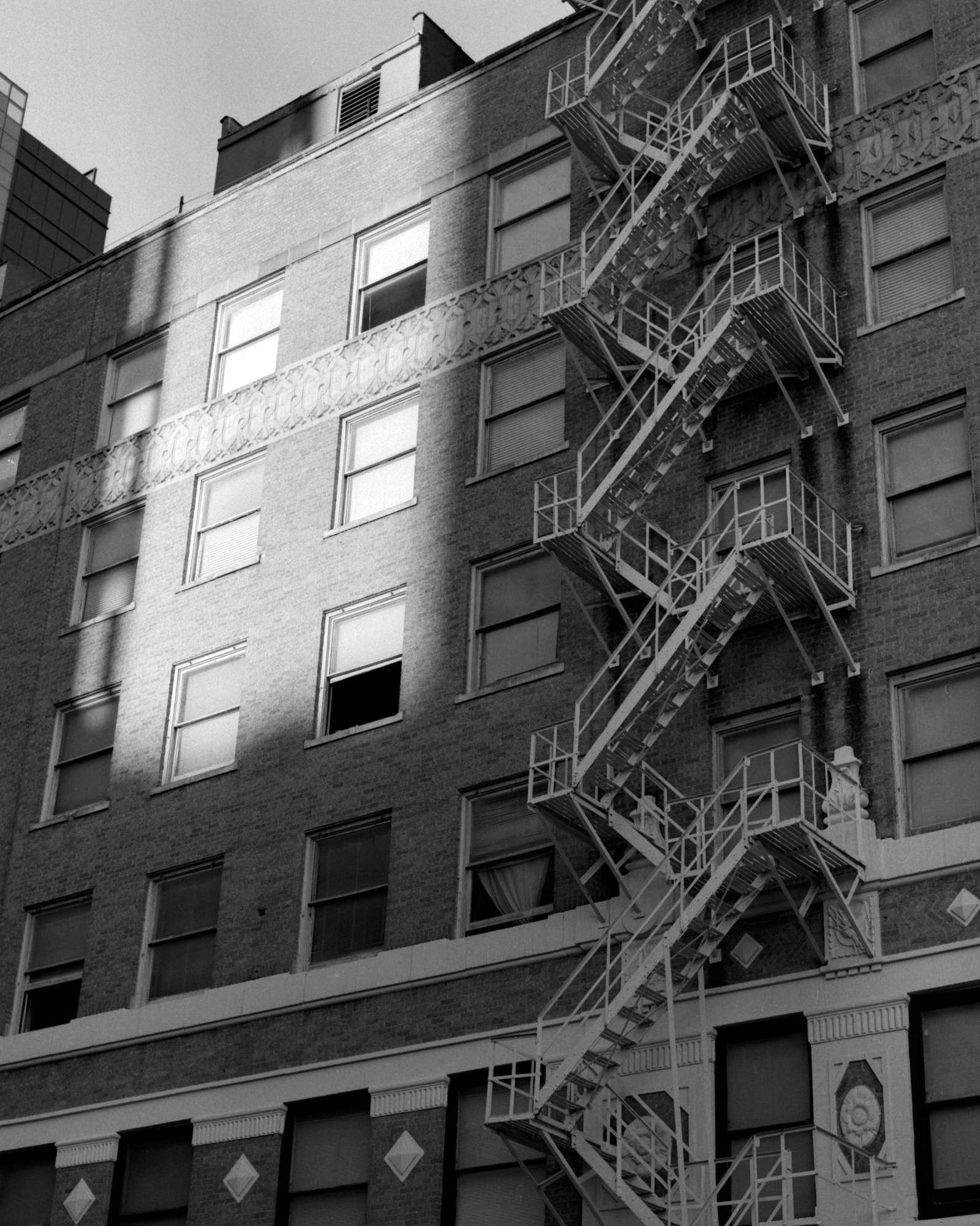 Photo of fire escape with sunlight hitting the windows on high rise building