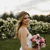 The bride with a half-up and half-down hairstyle looking over her should hold a bouquet. 
