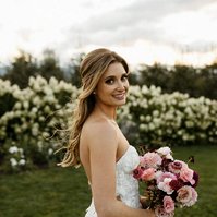 The bride with a half-up and half-down hairstyle looking over her should hold a bouquet. 
