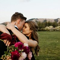 Beautiful bride hugging groom and holding a flower bouquet. 