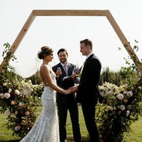 The bride and groom hold hands during the ceremony with elegant hair updo. 