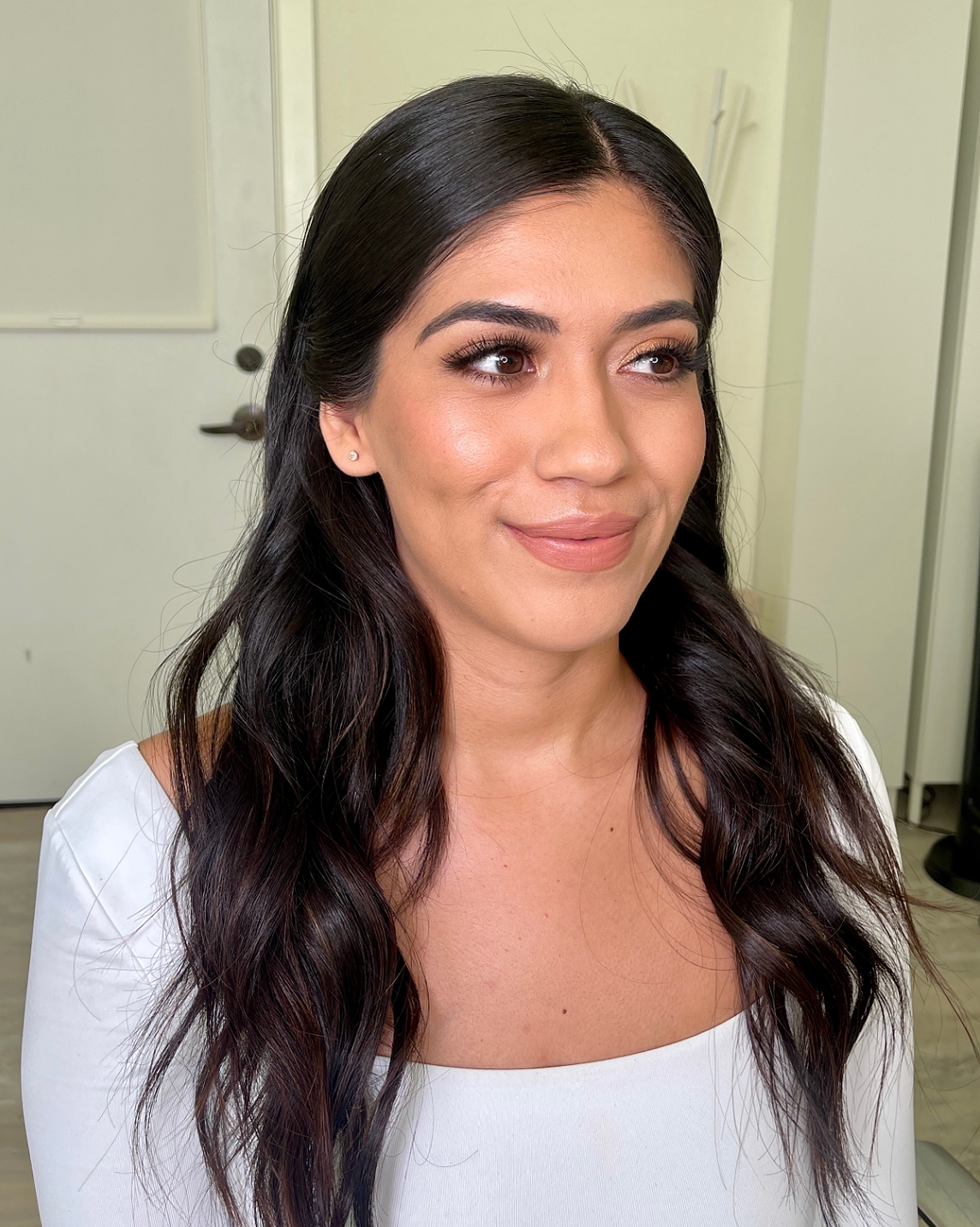 strong brow makeup look and soft wavy hair tuck behind ears.