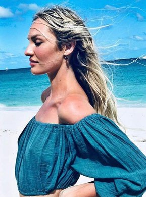Supermodel Candice Swonpol at Turks and Caicos beach wearing a turquoise off-the-shoulder top as wind blowing on her hair.