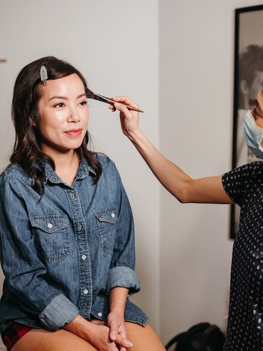 An Asian makeup artist is working behind the scene on the Asian wedding bride.