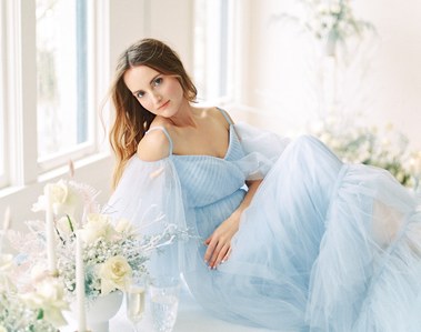 Girl in the blue dress posing on the wedding table. She has beautiful natural flowy hair