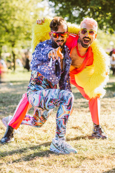 Two extravagantly dressed men pose and point at the camera. 
