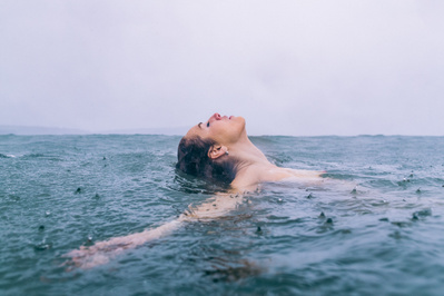 A woman bathing in a rain shower in the sea. 