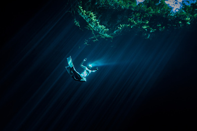 Underwater free diver reflecting the light of the sun with her mask 