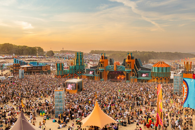 A shot of a music festival at dusk containing thousands of people. 