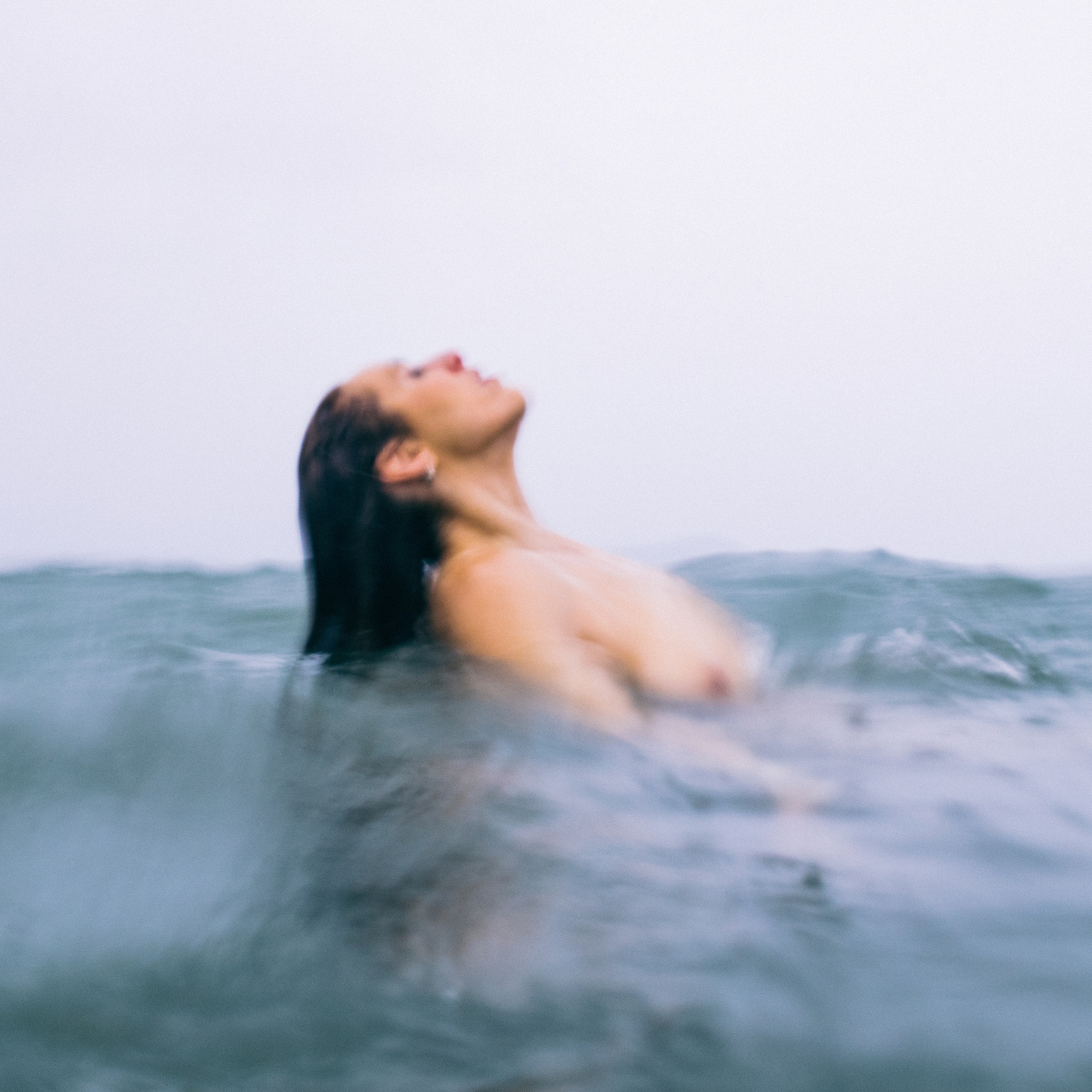A naked woman bathes in a rain shower in the sea