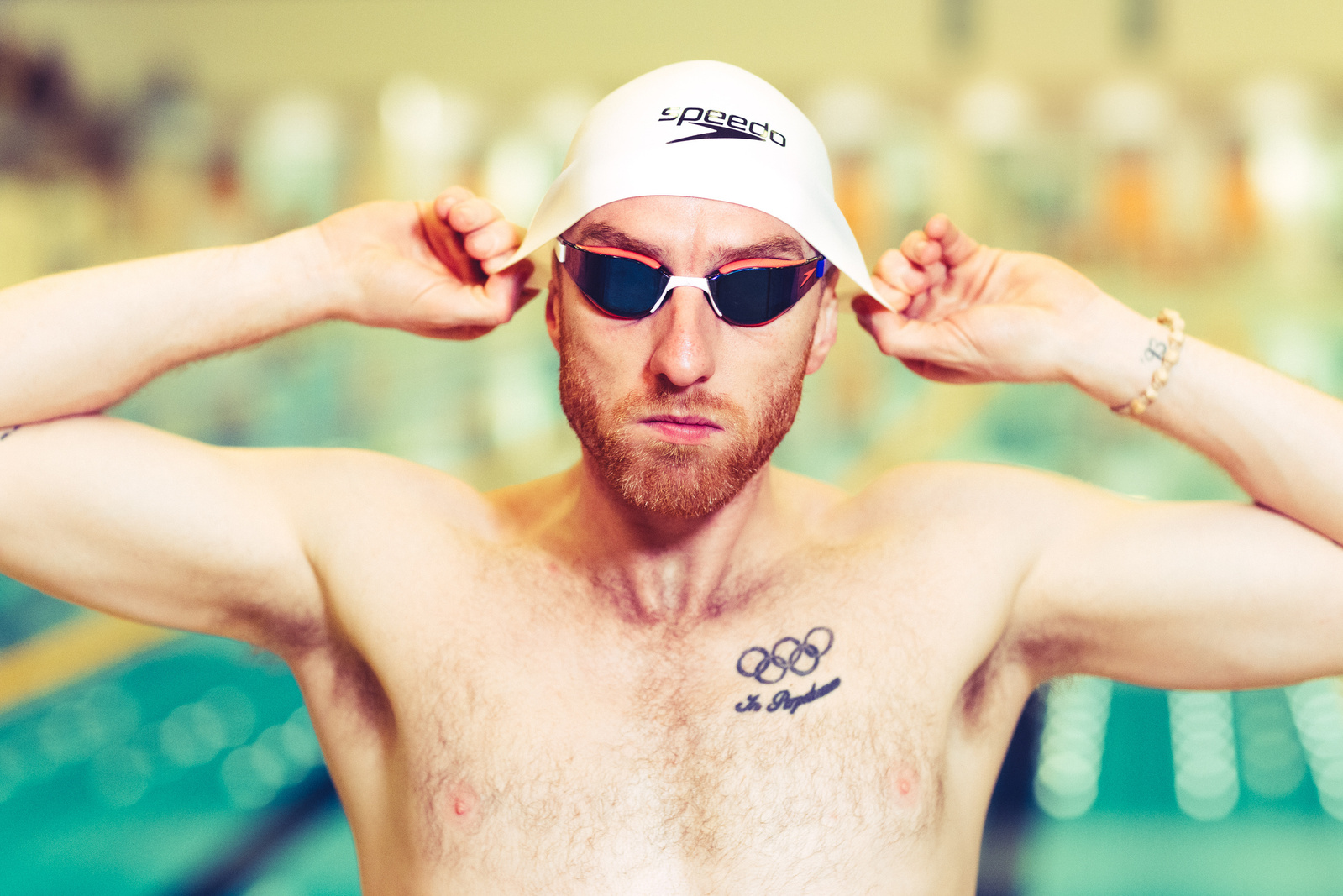 Olympic Swimmer Dan Wallace puts on swim cap in front of pool 