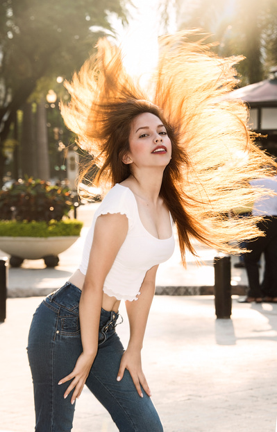 Young female model flipping hair into sun during a portrait photography shoot in streets of Orlando.