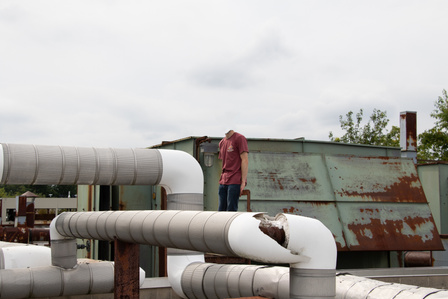 A headless android stands idly on the roof of the lab it was created in 