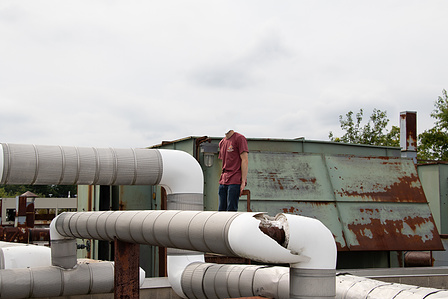 A headless android stands idly on the roof of the lab it was created in 