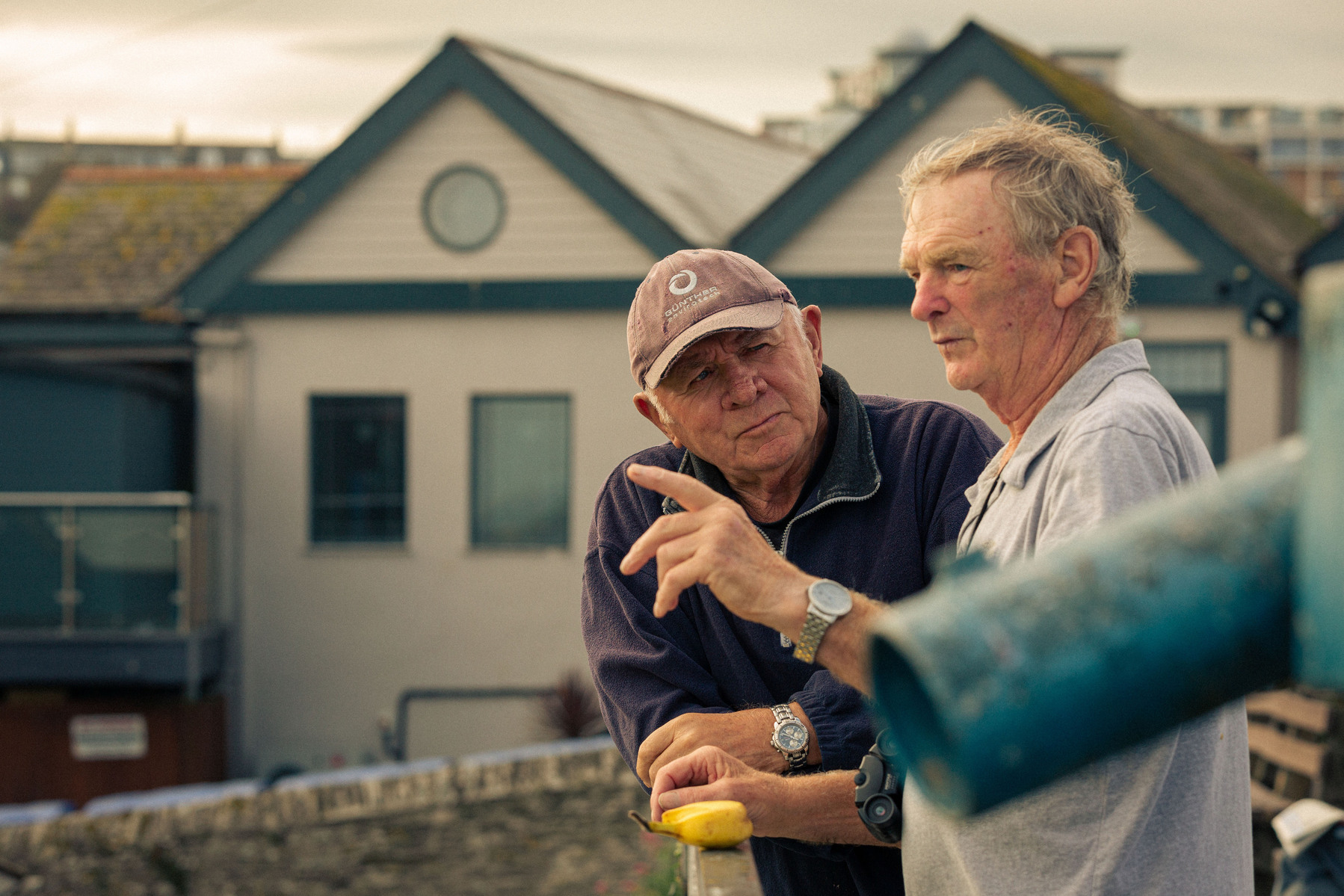 Newquay West End Bowls Club playing at their location above the Newquay harbour, in Cornwall, Western England. Alan, who looks after the club, chats to a member of the public.