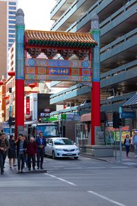 China town Melbourne, with car in background and people on a foot path.