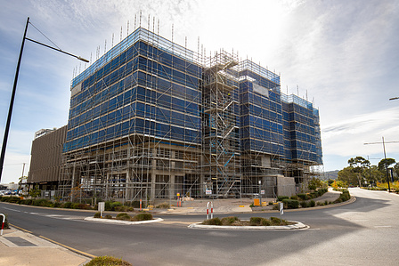 Construction site, with scaffolding clear blue skies and bitumen road.